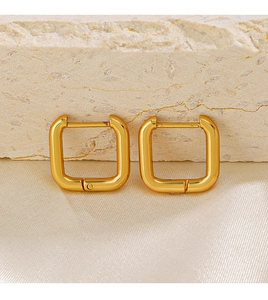 Macro shot of 18K gold plated square geometric earrings on a textured stone background