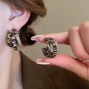 Close-up of vintage leopard print hoop earrings showing layered acrylic design and texture