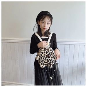 Detail of plush leopard print mini backpack with soft faux fur and white straps on a child