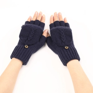 Dettaglio dei guanti in maglia blu navy con trama a trecce e chiusura con patta a bottone