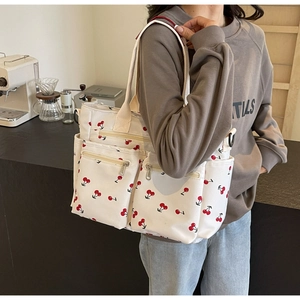 Detailed view of white canvas tote bag with red cherry print and zipper pocket design