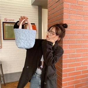 Quilted daisy pattern light blue tote bag with pink handles shown in a lifestyle scene