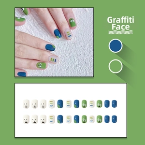 Macro view of 24pcs handmade press-on nails with graffiti sad face patterns and blue stripes