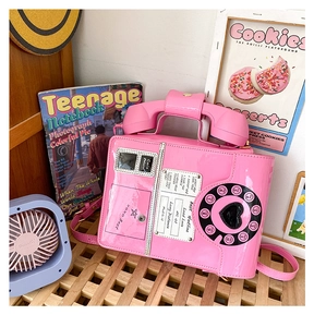 Close-up of pink retro telephone shaped crossbody bag with vintage dial on a wooden table