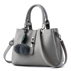 Grey pebbled faux leather handbag with white geometric stitching and pom-pom charm
