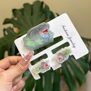 Close-up of cute grey acrylic hippo hair clips with blue bow details on display card