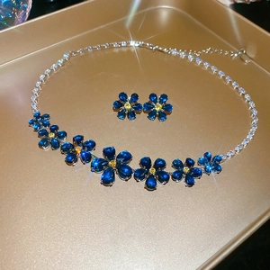 Close-up of blue zircon flower jewelry set with necklace and studs on golden tray