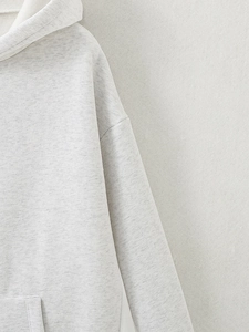 Detail of light grey hooded sweatshirt showing the hood seam and textured knit cotton fabric