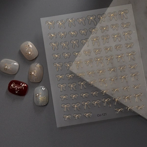 Détail de stickers à ongles nœuds dorés avec finition métallique et motifs en 3D