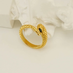 Vintage gold snake ring with scale texture and black gemstone on artistic background