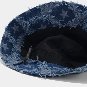 Macro detail of distressed frayed edges and star print on blue denim bucket hat