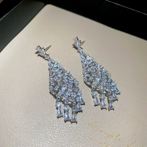 Détail de boucles d'oreilles pendantes argentées avec pierres en zircon étincelantes