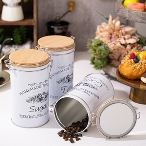 White tinplate kitchen canisters set with wooden lids for coffee sugar and tea storage