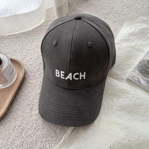 Detail of embroidered 'BEACH' lettering on dark grey cotton baseball cap texture