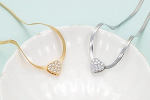 Detailed close-up of gold and silver heart pendants with cubic zirconia on snake chains