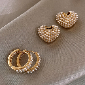Dettaglio dei ciondoli a cuore in perla su orecchini a cerchio placcati in oro