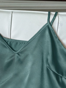 Nahaufnahme des petrolblauen Satin-Tops mit seidiger Textur und V-Ausschnitt-Details