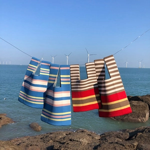 Knitted tote bags with stripe patterns hanging by the sea showing fabric texture