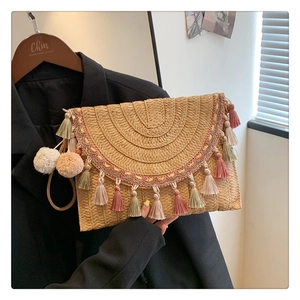 Detail of straw woven envelope clutch bag featuring multi-color fringe and tassel trim