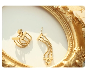 Detail of 18k gold plated triple layer bead chain fringe earrings on a vintage frame
