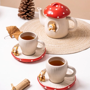 Detail view of cute red mushroom ceramic teapot and cups with 3D squirrel decorations