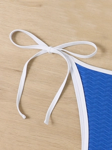 Close-up of royal blue bikini with wavy texture and white contrast side tie detailing