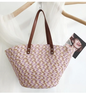 Detail of colorful purple and beige woven straw tote with brown faux leather handles