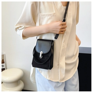Détail d'un sac à bandoulière noir avec boucle argentée porté par un mannequin