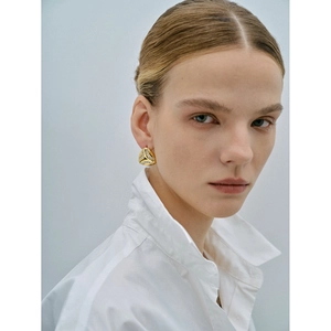 Macro detail of gold-plated geometric earrings featuring pave-set cubic zirconia accents