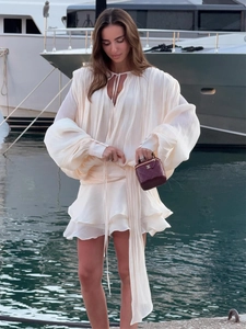 Elegant white chiffon lantern sleeve mini dress with ruffle details in a resort setting