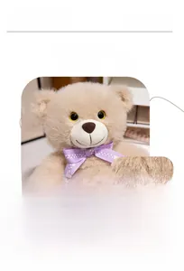 Detail of khaki teddy bear plush with purple polka dot bow and embroidered features