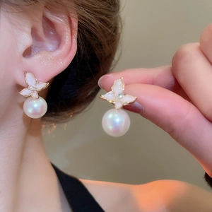 Gros plan sur des boucles d'oreilles fleur rose avec perles portées par un mannequin