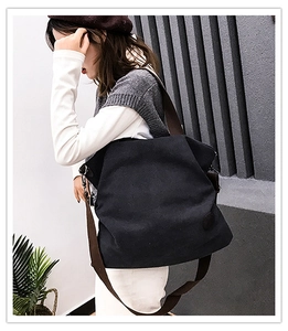 Vue détaillée du sac cabas en toile noire avec lanières marron porté par un mannequin