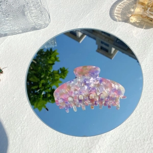 Macro view of a colorful marble textured acetate hair claw clip on a mirror surface