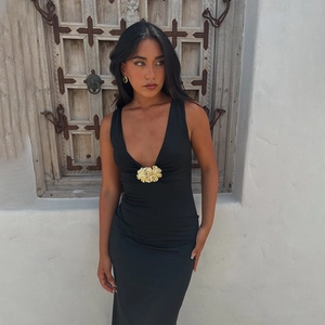 Detailansicht des eleganten schwarzen Maxi-Kleids mit tiefem V-Ausschnitt und Goldblume