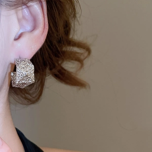 Close-up of minimalist silver-tone C-shape textured earrings worn by a model