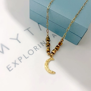 Detailed macro view of 18k gold moon pendant necklace on a blue jewelry gift box