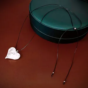 Minimalist silver heart pendant necklace with hammered texture and adjustable black cord