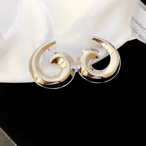 Polished silver spiral stud earrings with elegant snail shell design on silk background