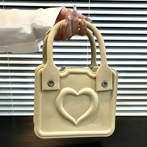 Detail of cream EVA beach bag with embossed heart pattern and silver metal eyelets