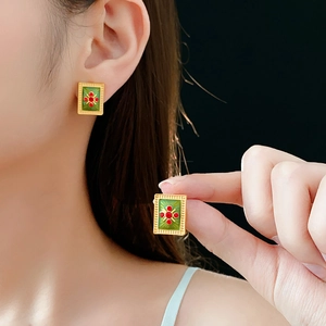 Detail of vintage gold rectangular earrings with green enamel and red flower patterns