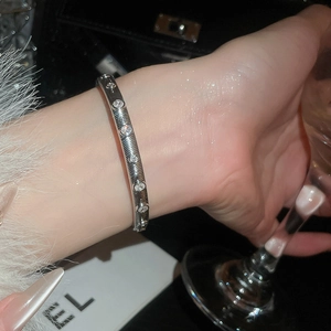 Detail of silver brushed texture bangle with round zircon stones in social setting