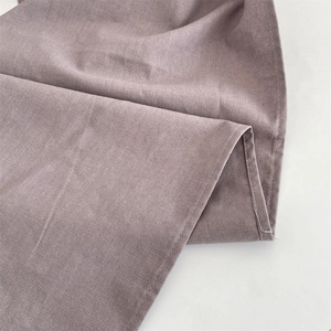 Primo piano della tovaglietta in lino color malva con bordi cuciti e trama naturale tessuta