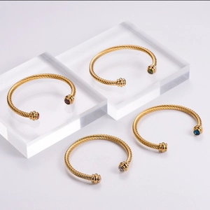 Vue détaillée de bracelets câbles torsadés dorés avec embouts en pierres colorées