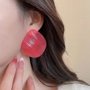 Modern oversized hot pink resin stud earrings with brushed texture on female model