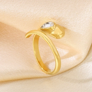 Close-up of golden snake ring with teardrop gemstone on beige silk background