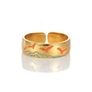 Detail of adjustable gold ring featuring orange bird and blue wave enamel patterns