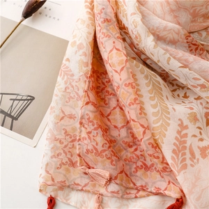 Macro detail of cotton-linen floral scarf showing orange wheat patterns and tassel trim