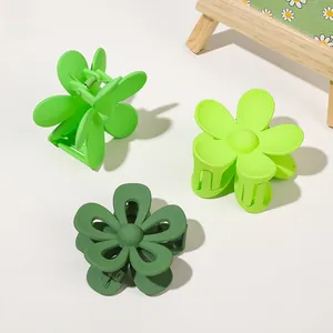 Detail of three matte green flower hair claws in different shades on a clean background