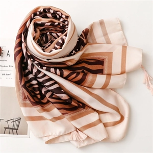 Detailed view of the zebra pattern texture and fringe trim on the brown silk scarf
